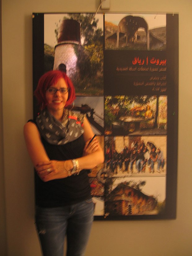 Lina Ghaibeh standing by a poster for her book