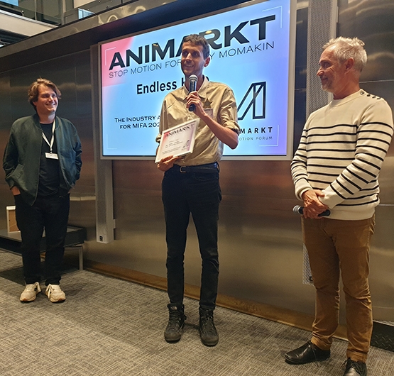 Production Tutor Christophe Erbes (Right) presenting the Industry Accreditation for MIFA 2024 to Konstantinos Vassilaros and Thomas Kunstler from Greece