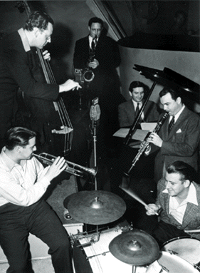 The Raymond Scott Quintette in Hollywood, 1938. Clockwise from top center: Dave Harris (tenor saxophone), Raymond Scott (piano), Pete Pumiglio (clarinet), Johnny Williams (drums), Dave Wade (trumpet), and Fred Whiting (bass).