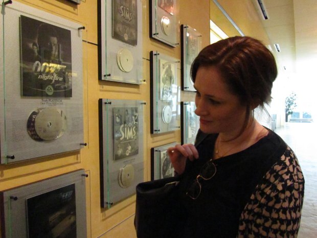 Head Over Heels producer Fodhla Cronin O'Reilly looks over a wall covered with EA game-launch plaques.